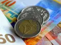 Münzen und Banknoten, darunter ein 2-Euro-Stück und Schweizer Franken. So lässt sich der Urlaub auszahlen!