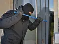 Einbrecher versucht, eine Tür mit einem Brecheisen aufzuhebeln. Wichtig für die Hausratversicherung: Nachweis von Bargeld und Wertgegenständen.