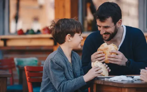 Vater und Sohn teilen sich ein Brot. Vielleicht plant der Vater ein Wechselmodell, um Unterhalt zu sparen, aber im Moment genießen sie die gemeinsame Zeit.