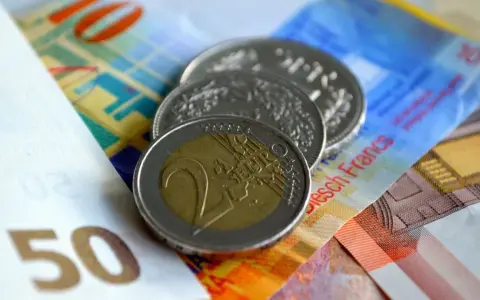 Münzen und Banknoten, darunter ein 2-Euro-Stück und Schweizer Franken. So lässt sich der Urlaub auszahlen!