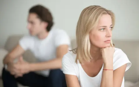 Ein Paar sitzt getrennt auf einem Sofa. Die Frau denkt nach, während der Mann abgewandt sitzt. Trennungsunterhalt steuerlich absetzbar ist ein wichtiges Thema.