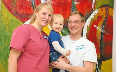 Glückliche Familie vor bunter Kunst. Das Bild thematisiert das Arbeitsrecht bei Schichtarbeit mit Kind.