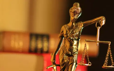 Justitia-Statue mit Waage und Schwert, symbolisiert Gerechtigkeit. Im Hintergrund unscharfe Bücher, die auf einen Fall mit 1/3 Betreuung hindeuten könnten.