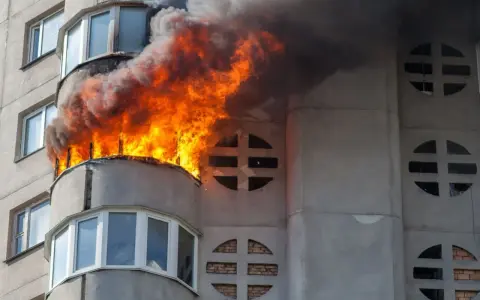 Flammen schlagen aus einem Balkon eines Wohnhauses. Ein Wohnungsbrand kann schnell passieren, eine gute wohnungsbrand versicherung ist wichtig.