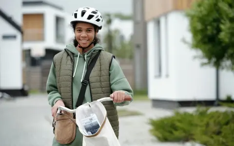 Junges Mädchen mit Fahrrad und Helm, bereit für ihre ersten jobs ab 14. Sie lächelt optimistisch in die Kamera.