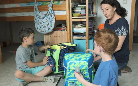 Mutter hilft ihren beiden Söhnen, Schultaschen zu packen. Ein Junge ist 16 Jahre alt.