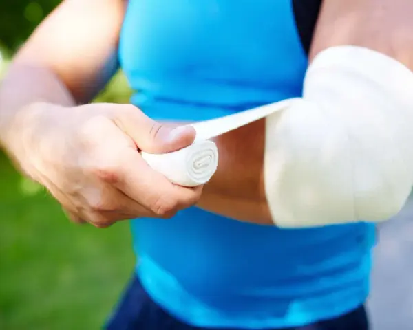Person bandagiert Arm. Frage: was zahlt die unfallversicherung bei sehnenriss?