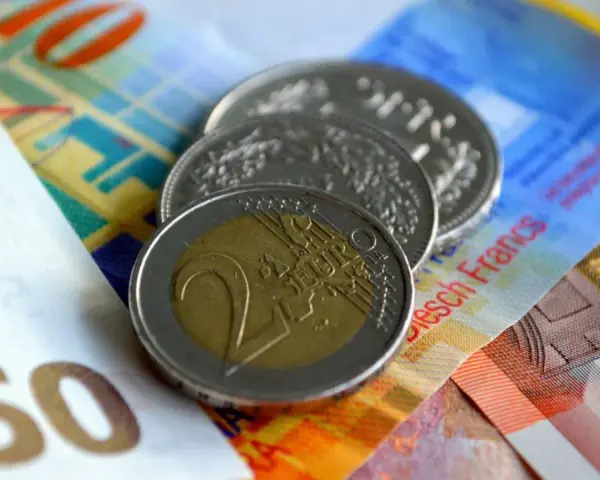 Münzen und Banknoten, darunter ein 2-Euro-Stück und Schweizer Franken. So lässt sich der Urlaub auszahlen!