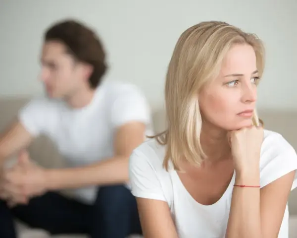 Ein Paar sitzt getrennt auf einem Sofa. Die Frau denkt nach, während der Mann abgewandt sitzt. Trennungsunterhalt steuerlich absetzbar ist ein wichtiges Thema.