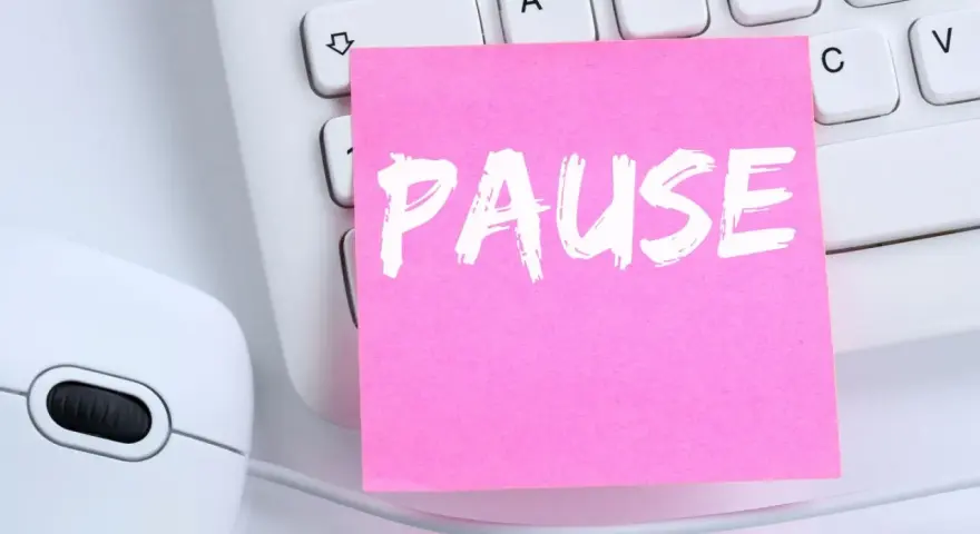 Ein rosa Zettel mit dem Wort "PAUSE" liegt auf einer Tastatur neben einer Maus. Ein Hinweis auf das **bildschirmpause gesetz**.