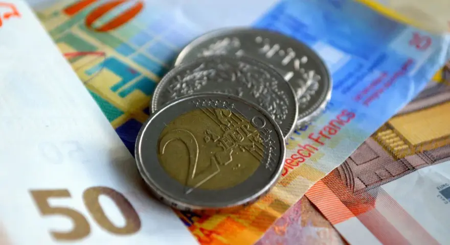 Münzen und Banknoten, darunter ein 2-Euro-Stück und Schweizer Franken. So lässt sich der Urlaub auszahlen!