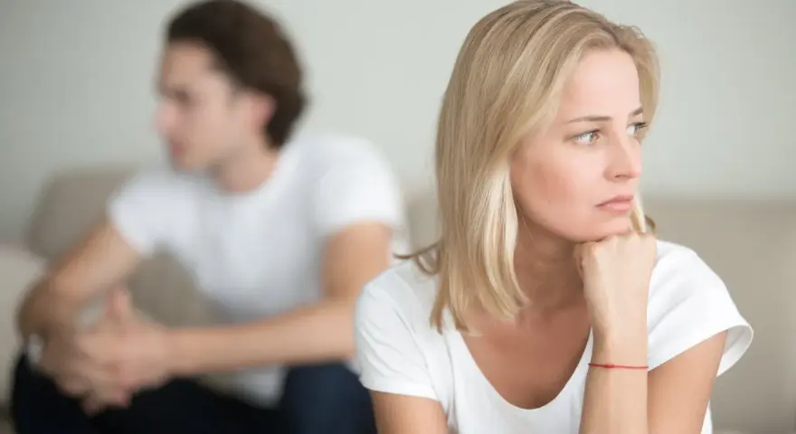 Ein Paar sitzt getrennt auf einem Sofa. Die Frau denkt nach, während der Mann abgewandt sitzt. Trennungsunterhalt steuerlich absetzbar ist ein wichtiges Thema.