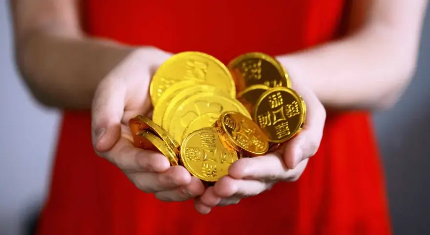 Hände halten einen Haufen glänzender Goldmünzen. Das ist ein schöner Gedanke, wann Urlaubsgeld!