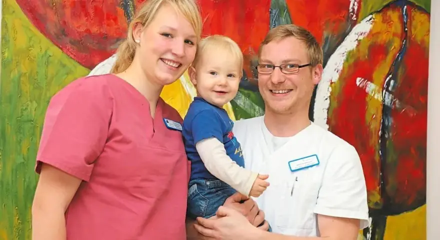 Glückliche Familie vor bunter Kunst. Das Bild thematisiert das Arbeitsrecht bei Schichtarbeit mit Kind.