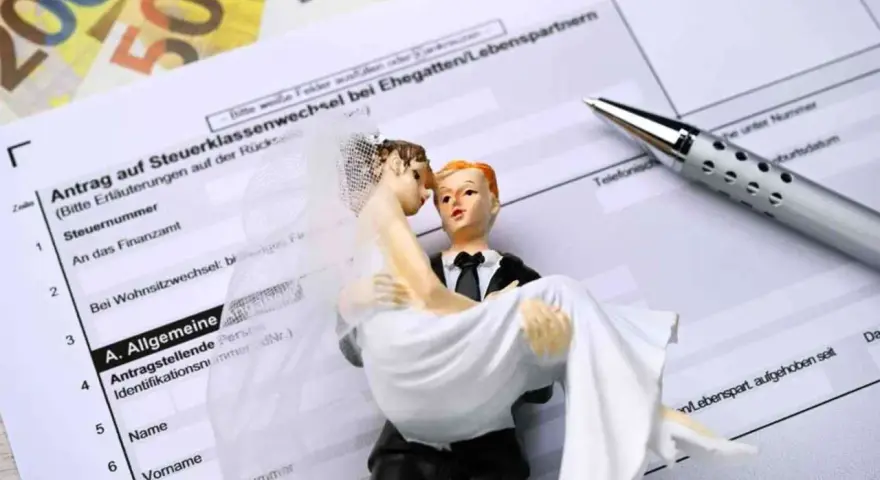 Hochzeitspaar auf Steuerformularen, die den Wechsel zur Steuerklasse 3 symbolisieren.