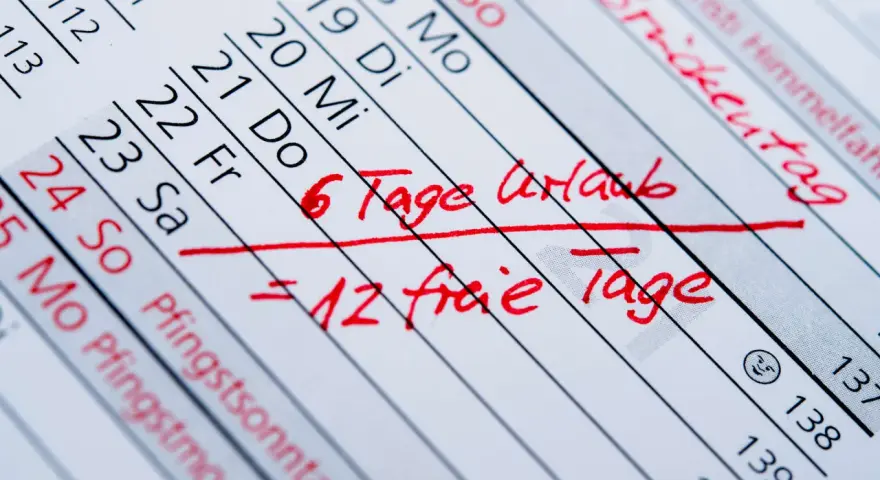 Kalenderblatt mit roten Markierungen: "6 Tage Urlaub = 12 freie Tage". Betriebsferien und Urlaubstage sind geplant.