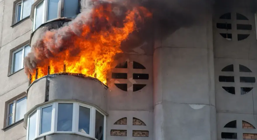 Flammen schlagen aus einem Balkon eines Wohnhauses. Ein Wohnungsbrand kann schnell passieren, eine gute wohnungsbrand versicherung ist wichtig.