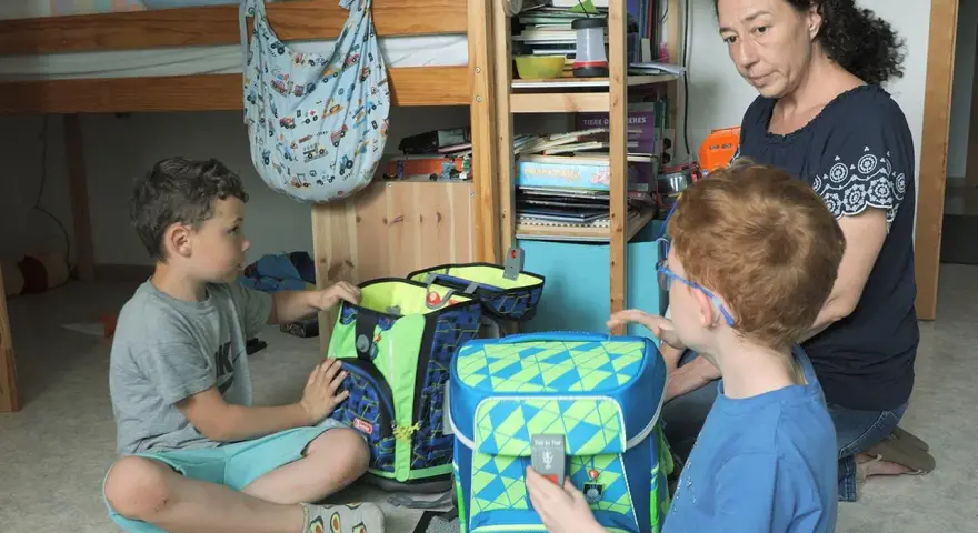 Mutter hilft ihren beiden Söhnen, Schultaschen zu packen. Ein Junge ist 16 Jahre alt.