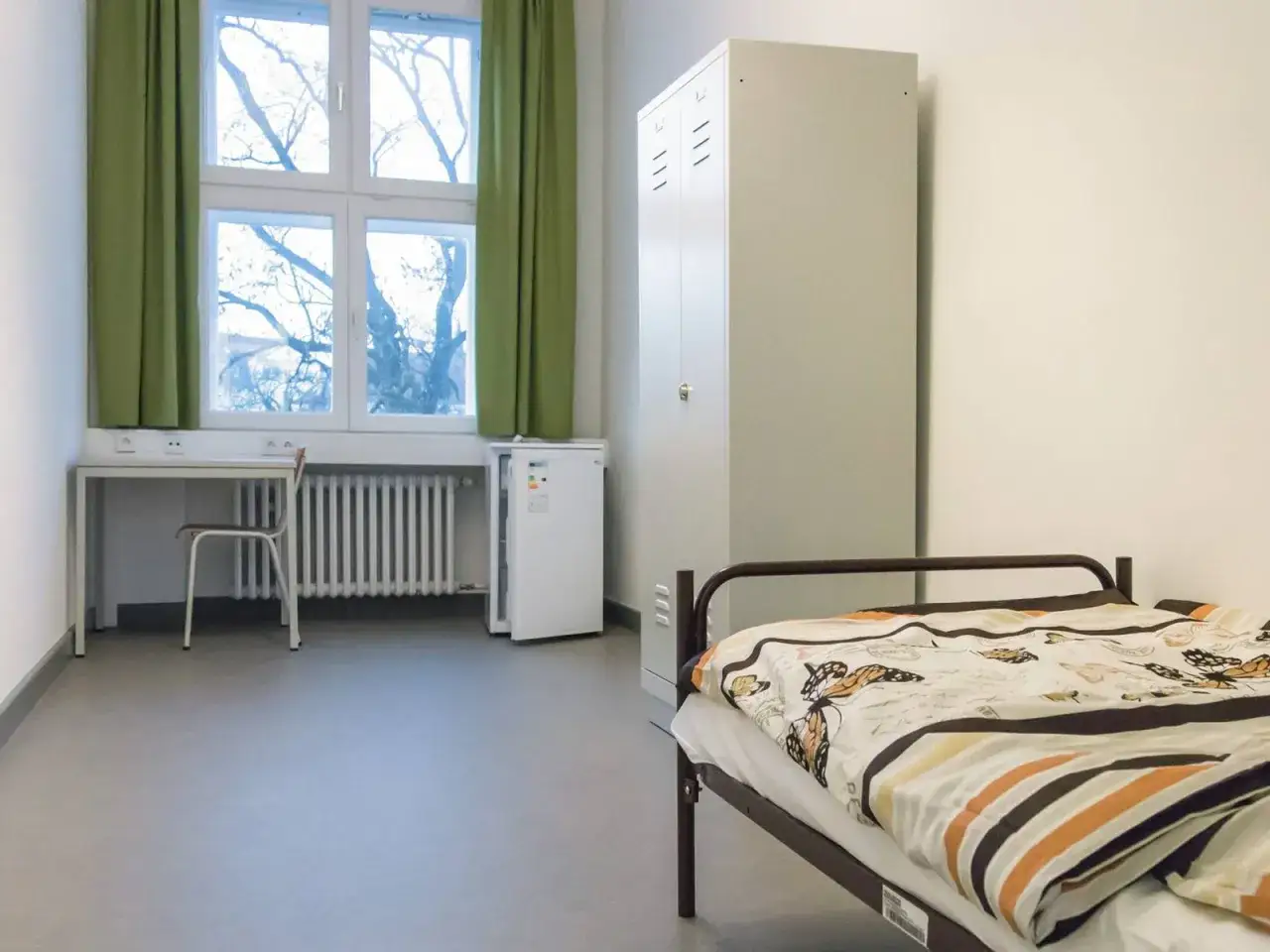 Ein einfaches Zimmer mit Bett, Schrank, Schreibtisch und K&uuml;hlschrank. Ein Ort, wohin ohne Geld und Wohnung?